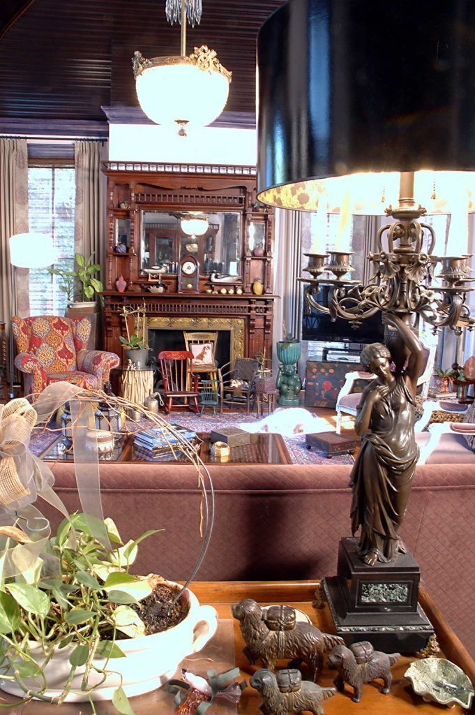 This historic preservation interior design, by Debby Gomulka, includes antique pieces, warm wood, rich fabrics and an ornate fireplace.